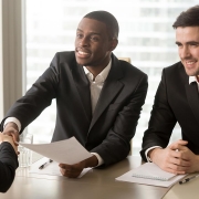 Two cheerful black and white recruiters welcoming female applicant on job interview, african and caucasian hr managers greeting candidate for vacant position, handshaking and good first impression